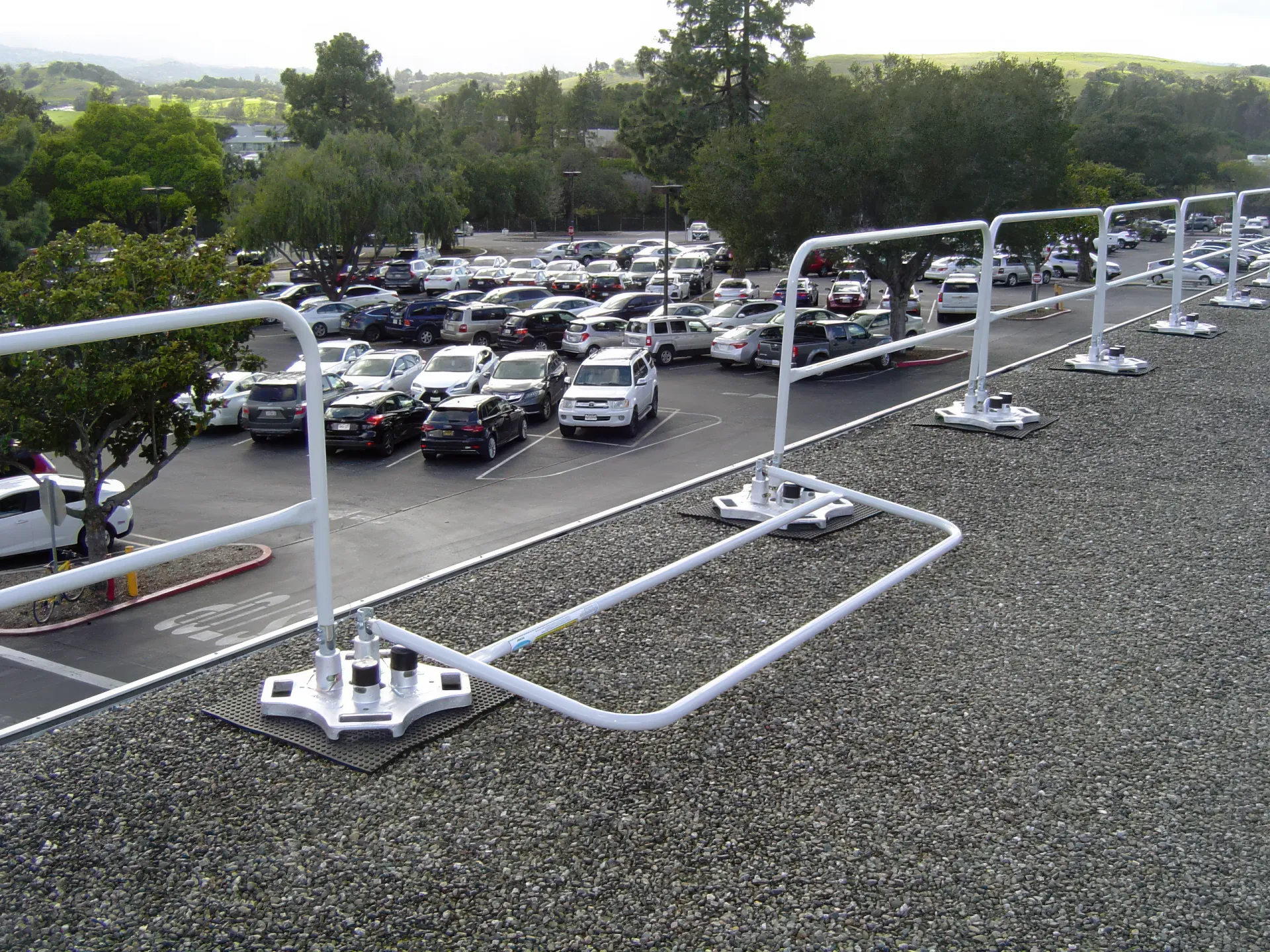 White freestanding guardrail on weighted bases along a gravel roof edge