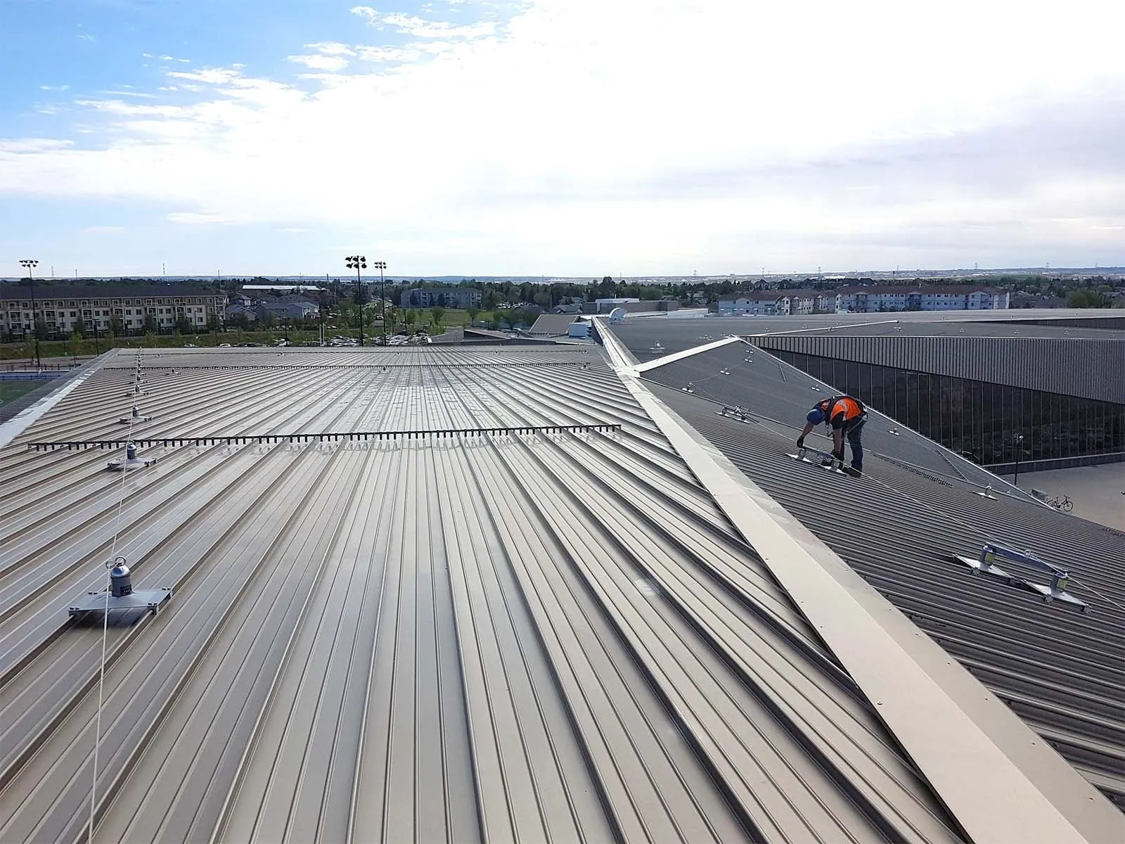 Technician secured with harness using rooftop guardrail for maintenance safety