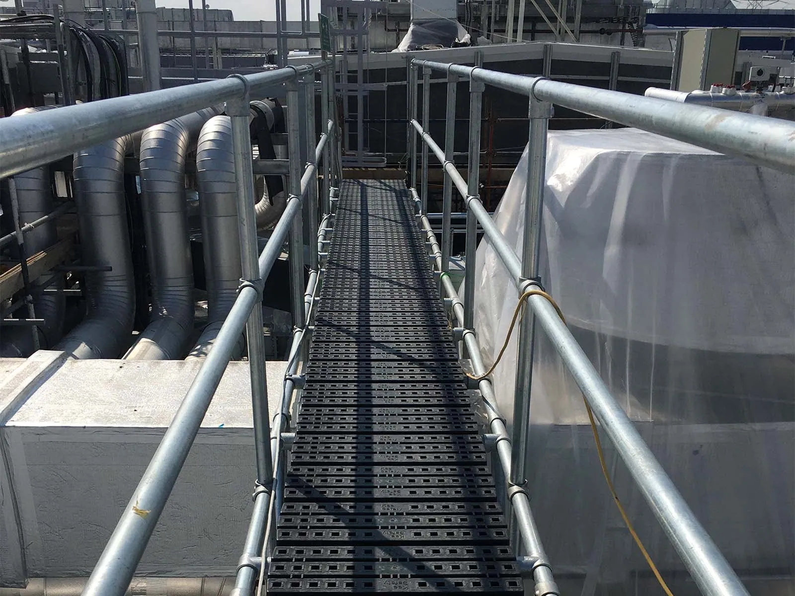 Elevated catwalk system with guardrails for safe access in industrial facility