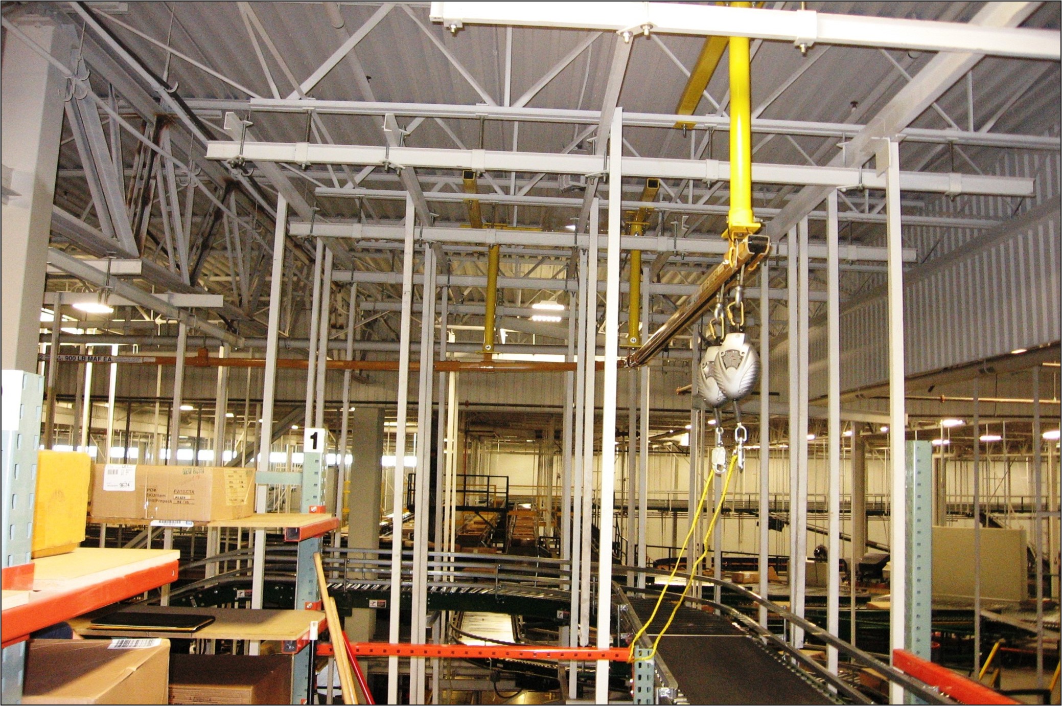 Rigid rail fall arrest system in distribution center providing continuous overhead protection