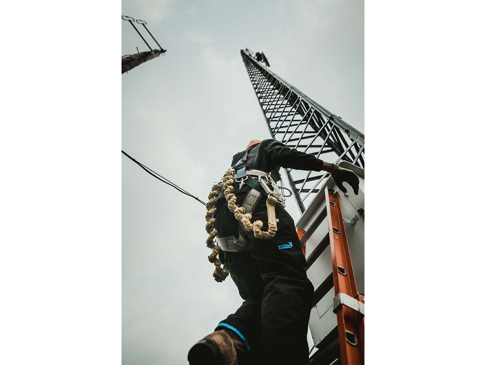Telecom worker climbing antenna tower using fall protection equipment