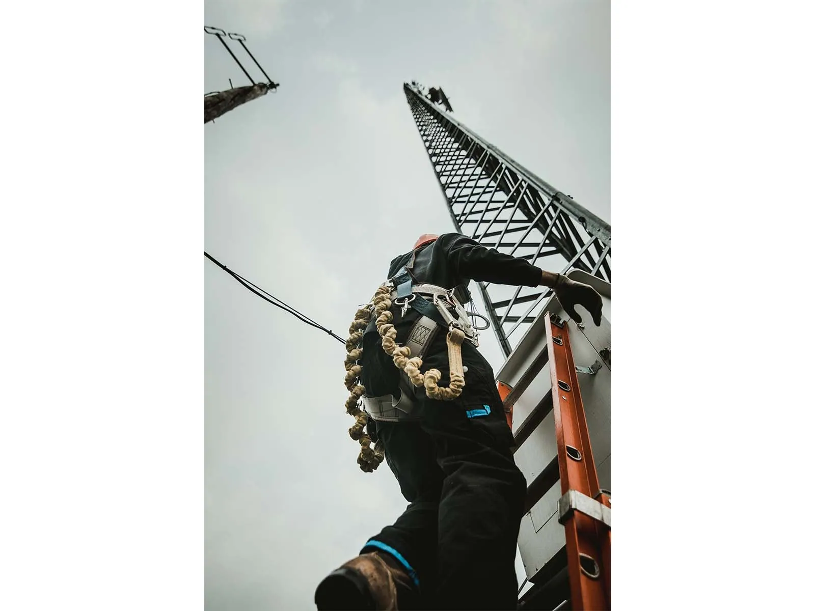 Telecom worker climbing antenna tower using fall protection equipment