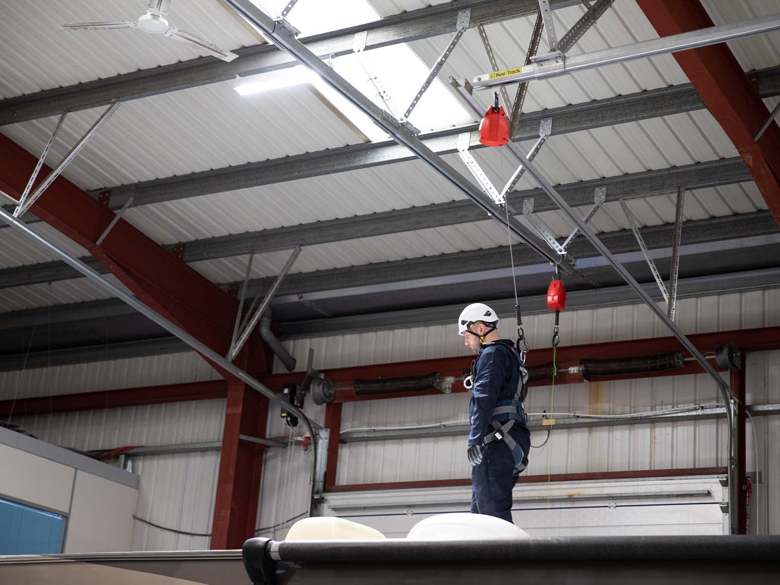 Rigid track fall protection system installed in industrial facility for safe elevated work