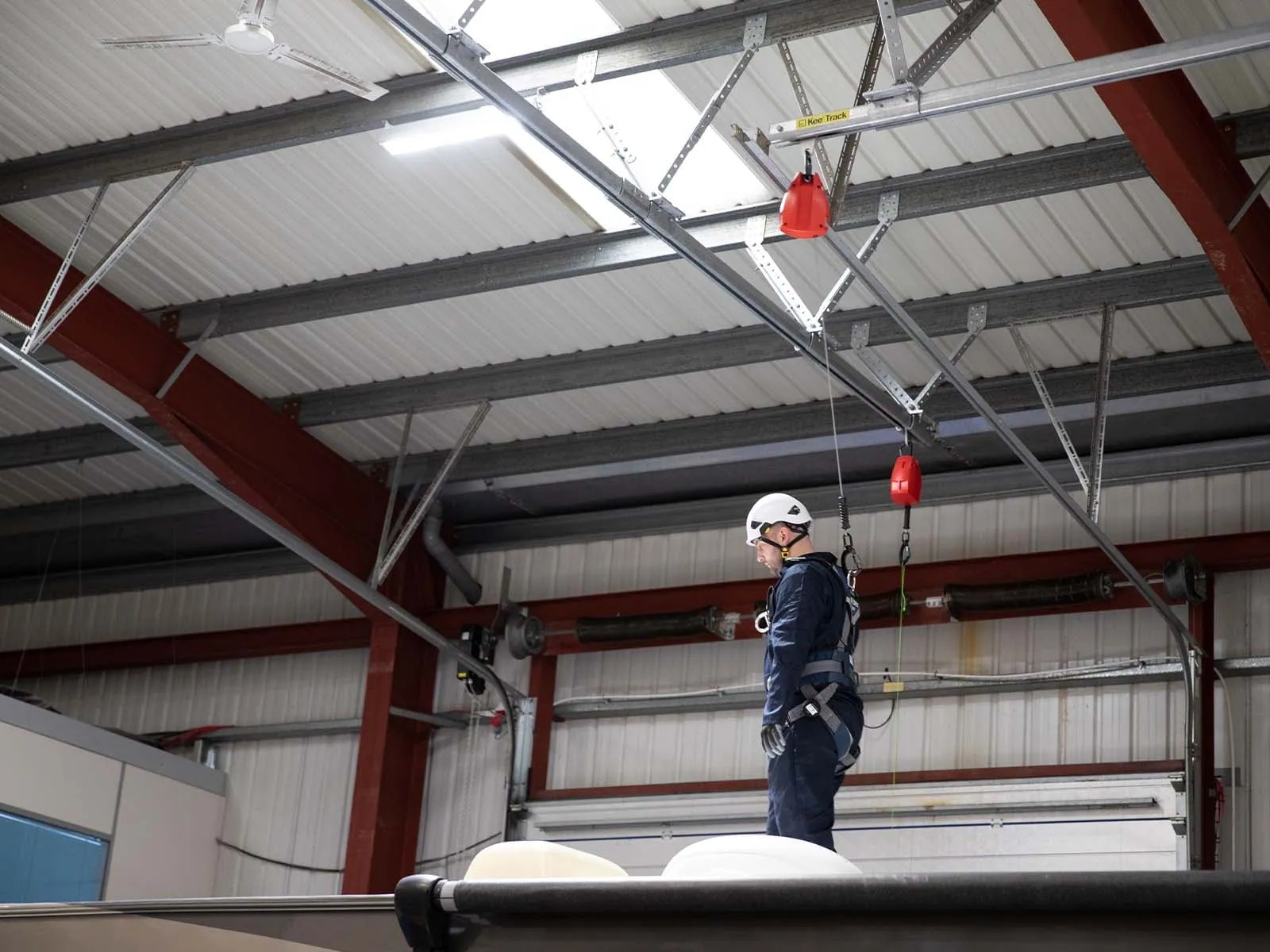 Rigid track fall protection system installed in industrial facility for safe elevated work