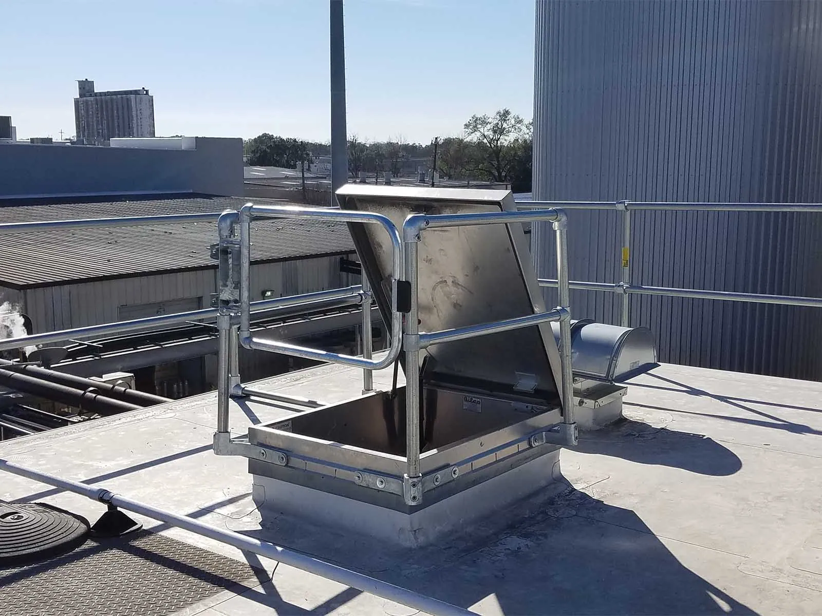 Guardrail system installed around roof hatch to prevent fall hazards