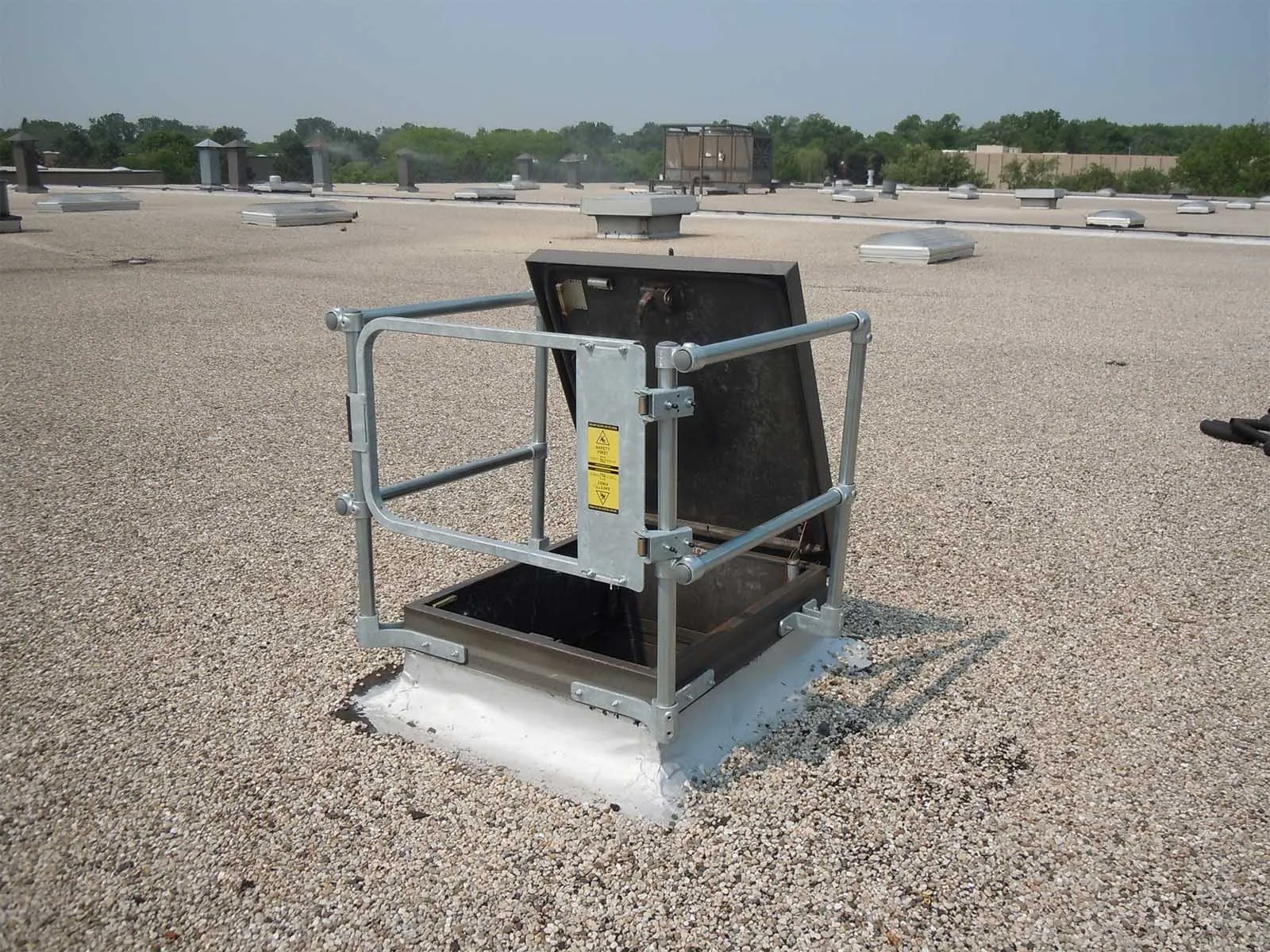 Guardrail system installed around roof hatch to prevent fall hazards
