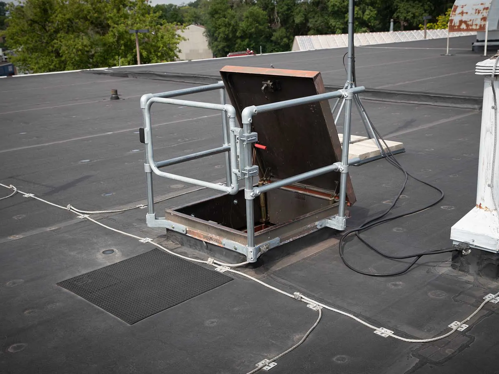 Guardrail system installed around roof hatch to prevent fall hazards