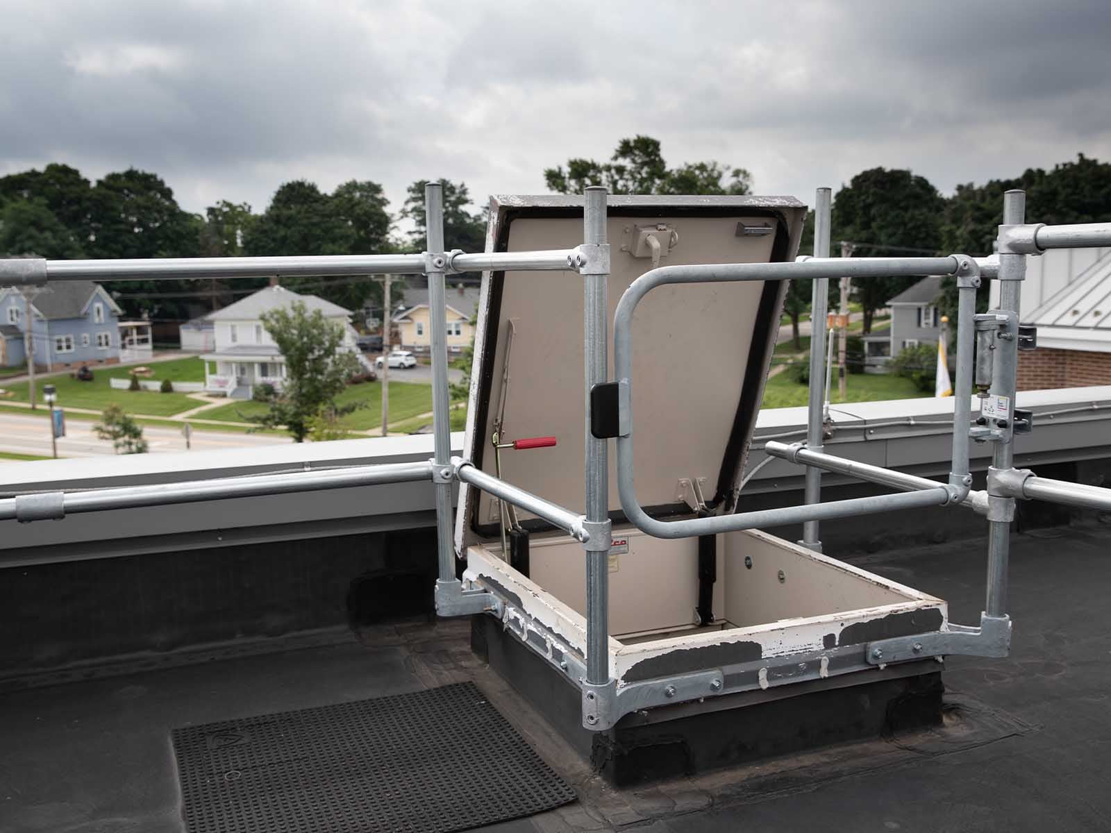 Guardrail system installed around roof hatch to prevent fall hazards