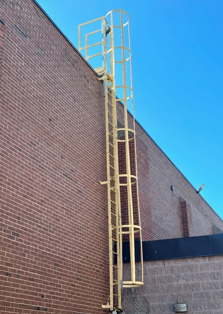 Yellow caged fixed ladder up a brick wall to the roof