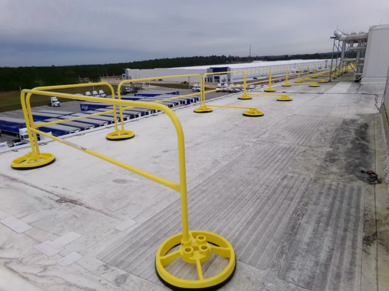 Yellow counterweighted guardrail along a large flat roof
