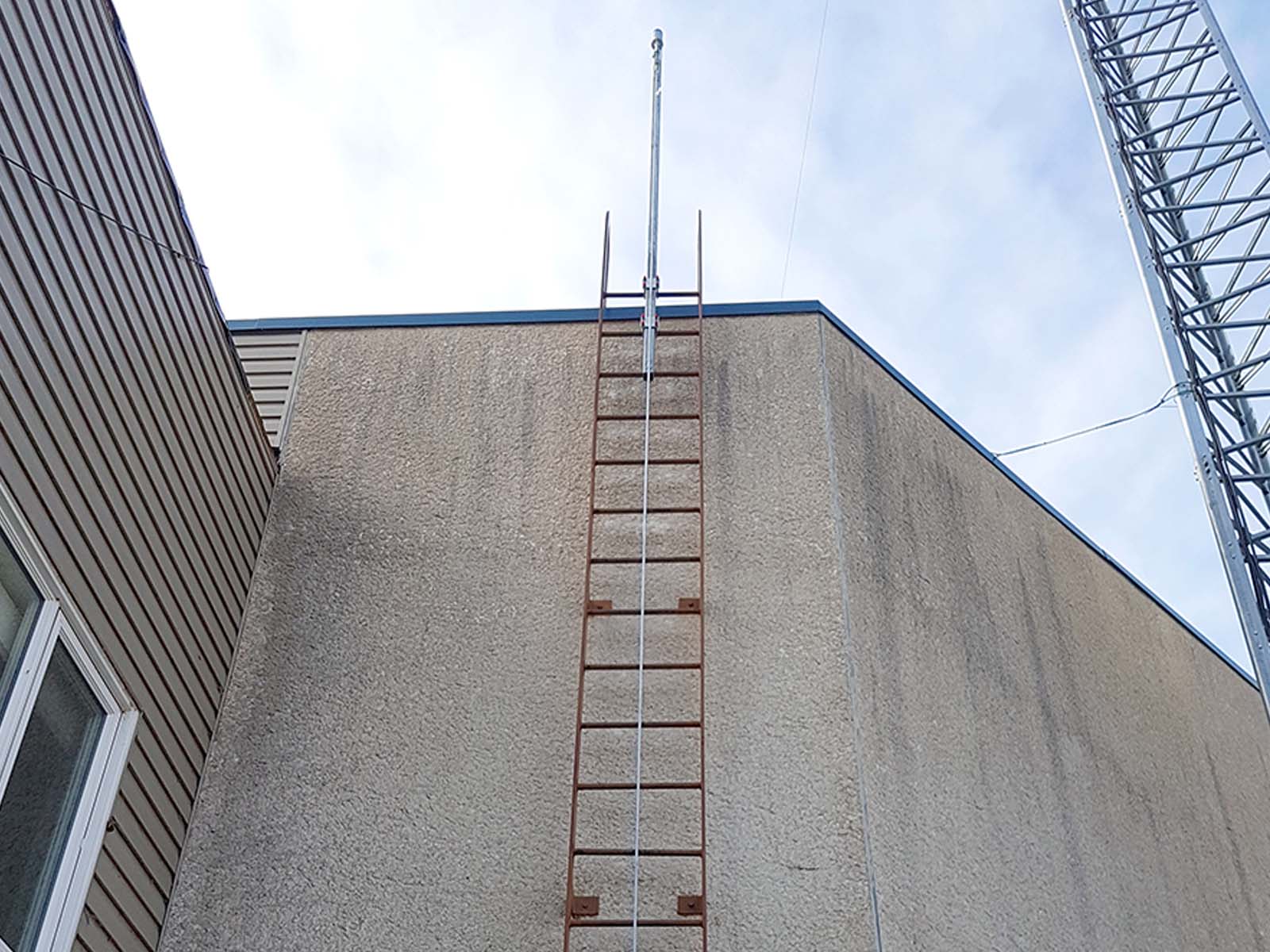 Fall protection system installed on exterior ladder for safe rooftop access