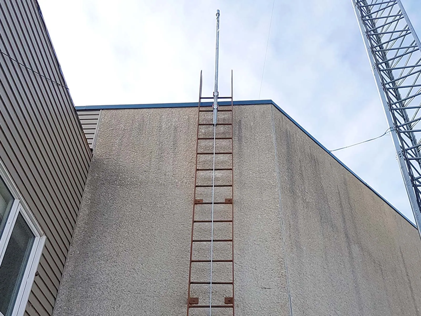 Fall protection system installed on exterior ladder for safe rooftop access