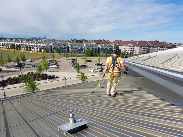 Worker in a full-body harness walking along a horizontal lifeline on a metal roof