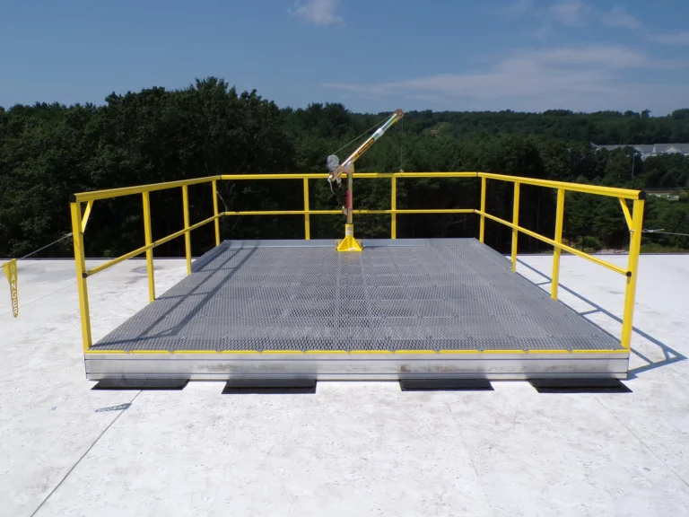 Grated rooftop platform with yellow guardrail and a davit arm