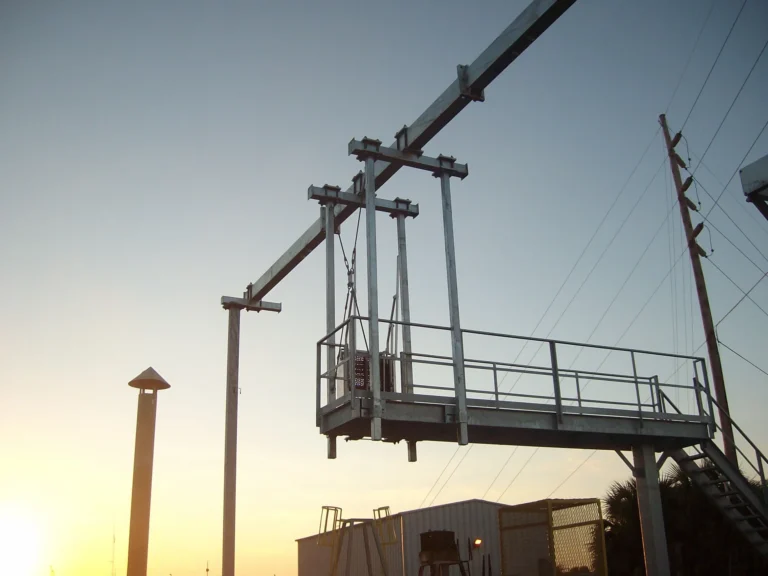 Access platform with guardrail hung from an overhead beam and silhouetted at sunset
