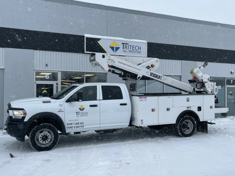 Tritech service truck with an aerial boom parked outside a shop in winter